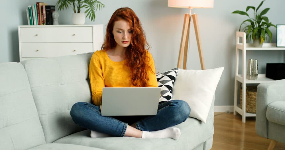 Woman on couch with laptop computer doing teletherapy