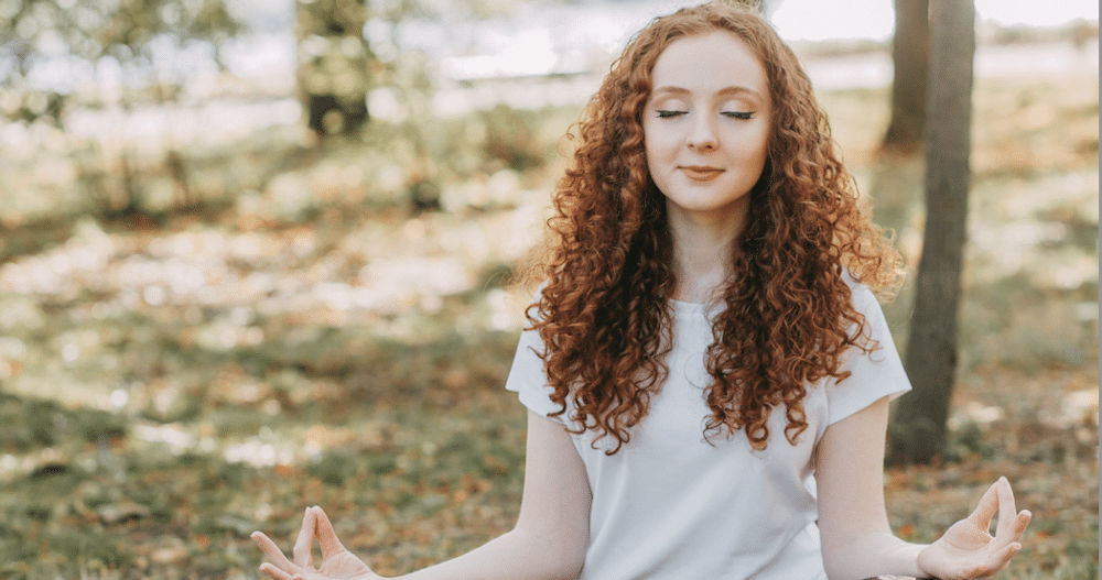 Woman seated outdoors practicing conscious breathing