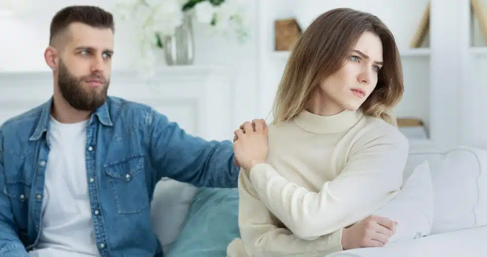 man consoling woman after argument sitting on a sofa