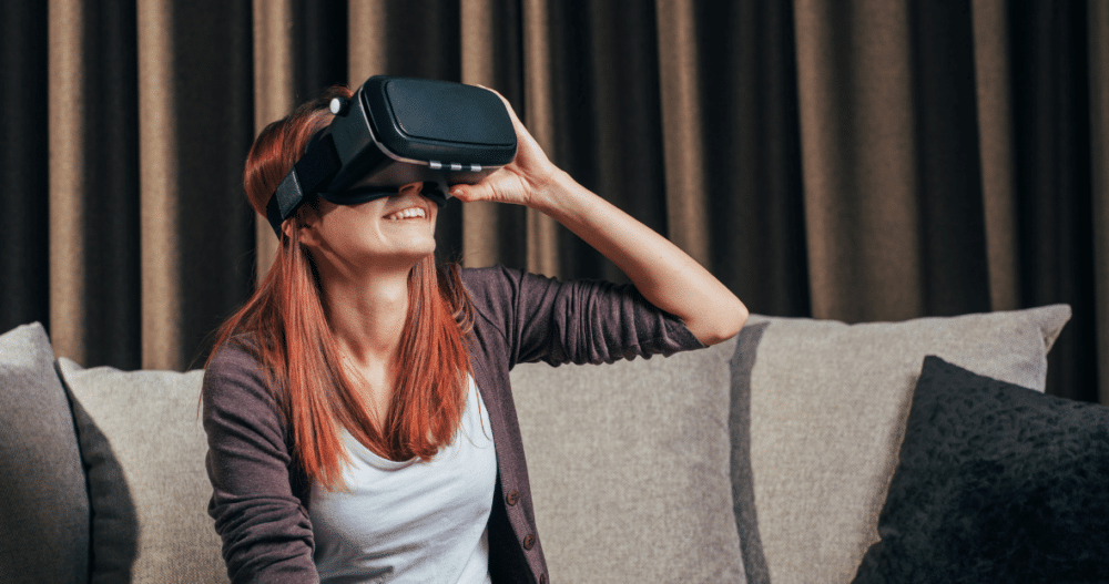 Woman sitting on a couch smiling while using a VR headset
