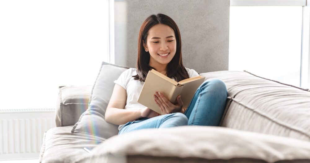 Woman sitting in bed smiling while reading a book