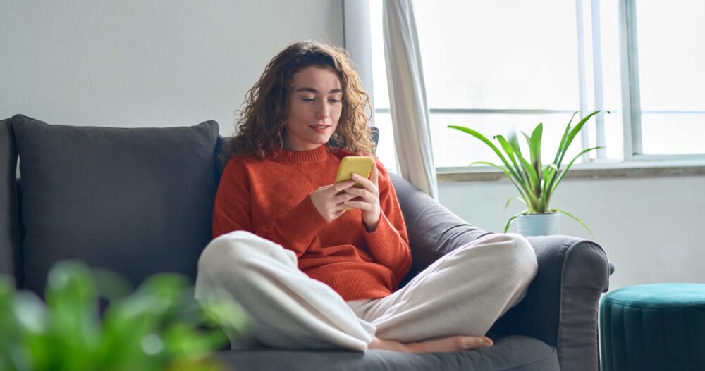 Woman sitting on a couch using social media on her phone