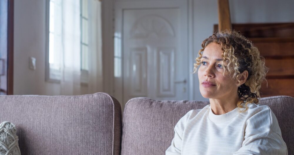 Woman sitting on the couch looking upward while deep in thought