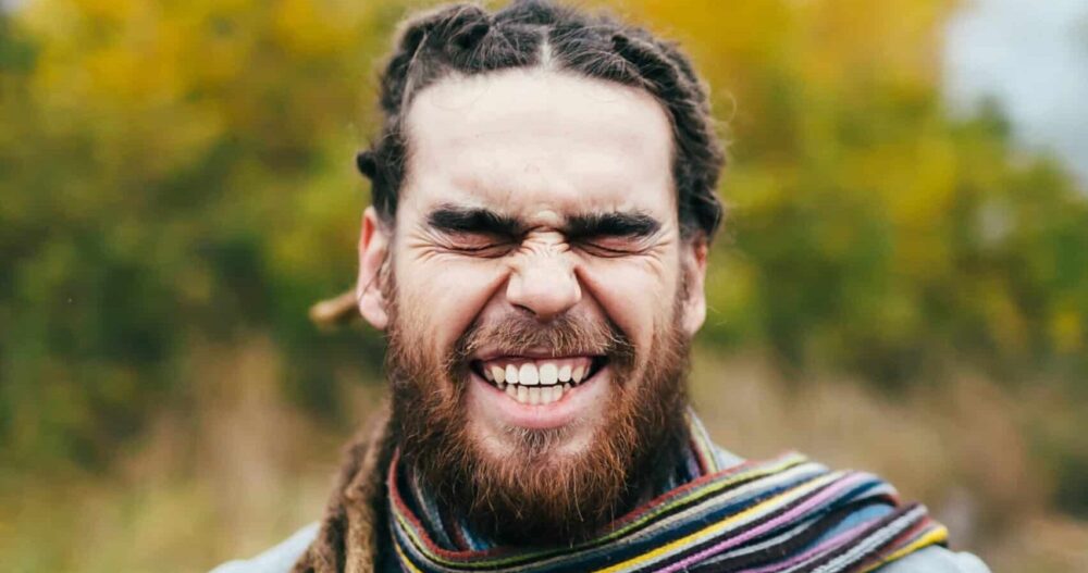 Man with long hair standing outside and smiling