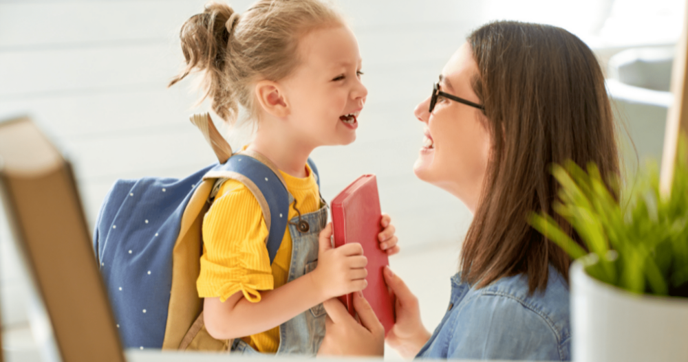 woman and her daughter looking at each other and smiling while the daughter gets ready to leave for school.