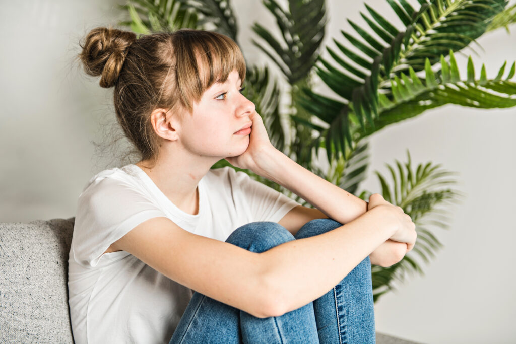 Teen girl sitting on the couch looking into the distance