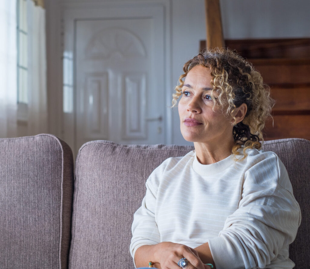 Woman sitting on the couch deep in thought looking out the window