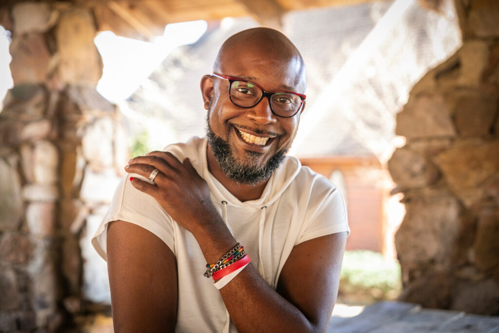 Black man in a white t-shirt sitting and smiling