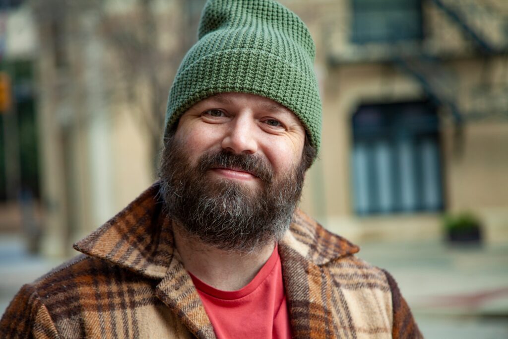 A happy bearded man wearing a beanie and flannel