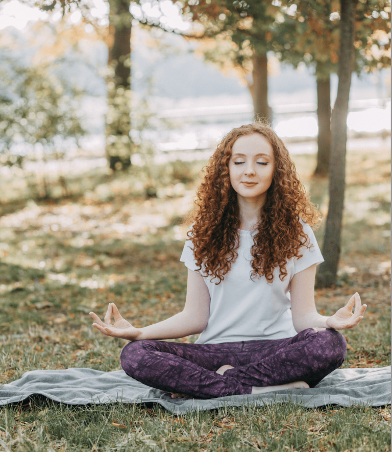 Woman seated outdoors practicing conscious breathing