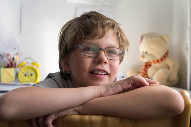 Close up portrait of tween boy with braces and eyeglasses smiling