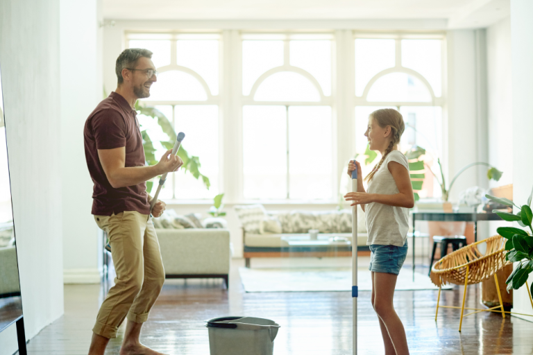 Father and daughter in their house doing spring cleaning while smiling