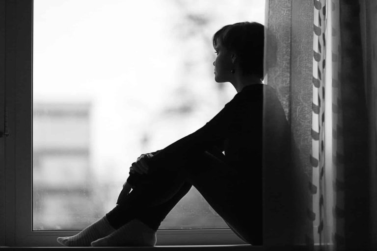 Woman sitting looking out the window longingly