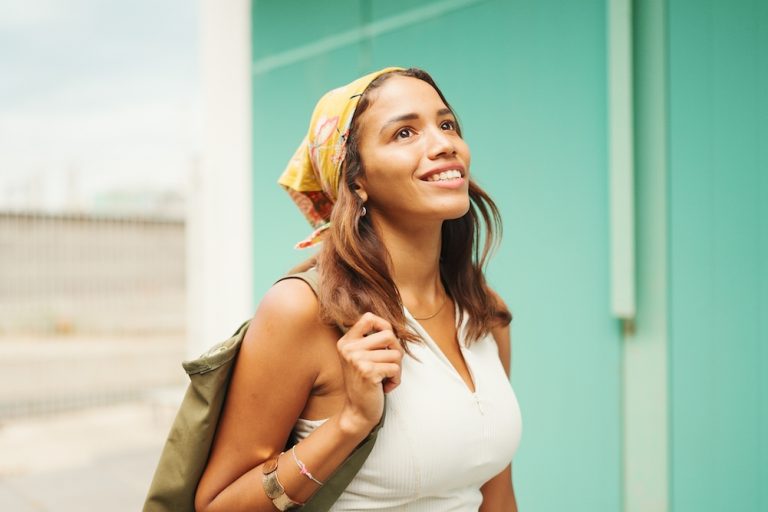 Woman with tanned skin, brown long hair wearing wireless headphones.