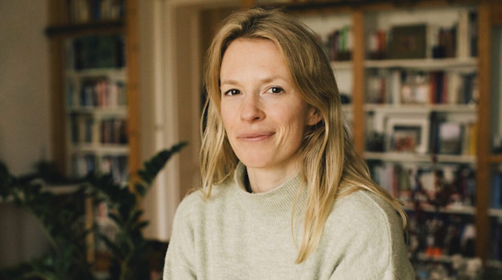 Portrait of blond woman wearing a grey sweater at home smiling