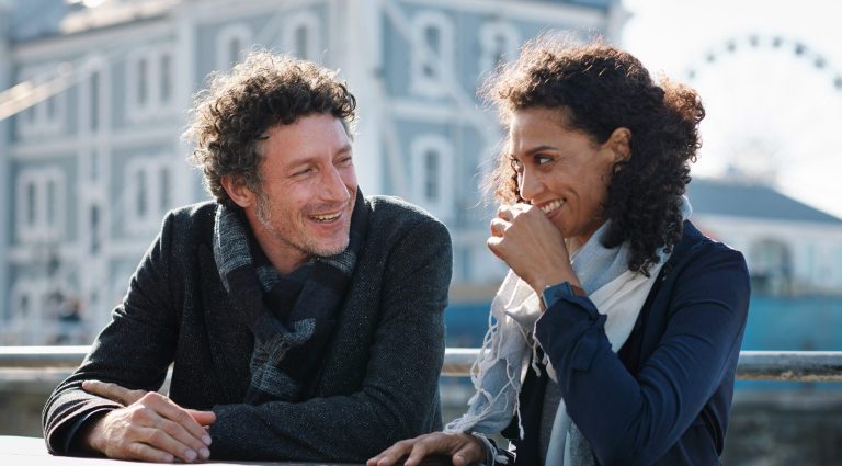 Man and woman standing outside talking and smiling