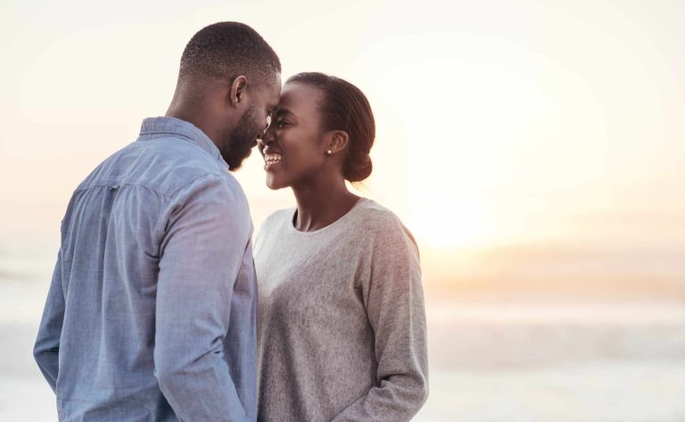 Couple holding hands and looking into each others eyes during sunset