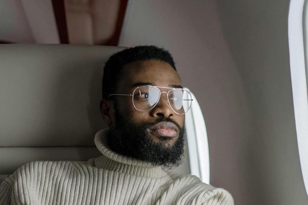 Man with glasses sitting on a plane looking out the window