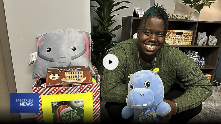 Dominique Mickler, a Therapist at our Ellie Mental Health St. Petersburg, FL Clinic standing in her office and holding a bunch of toys for her toy drive