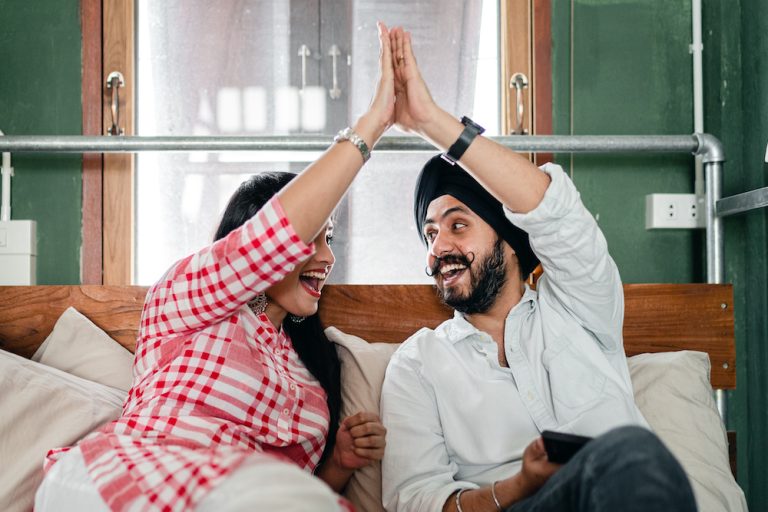 A couple sitting on a couch high fiving each other