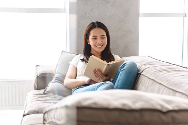Woman sitting in bed smiling while reading a book