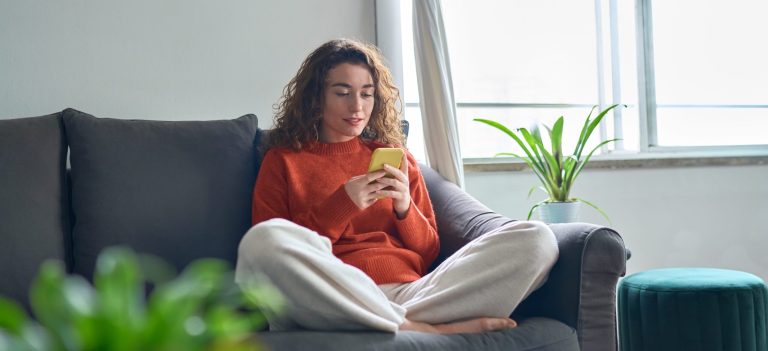 Woman sitting on a couch using social media on her phone