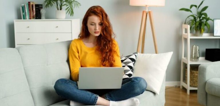 Woman on couch with laptop computer doing teletherapy