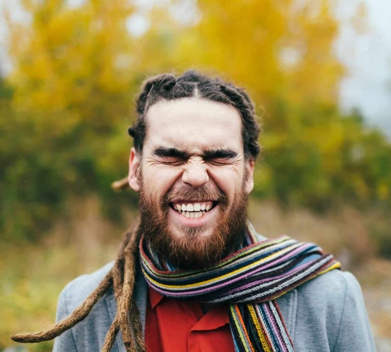 Man with long hair standing outside and smiling