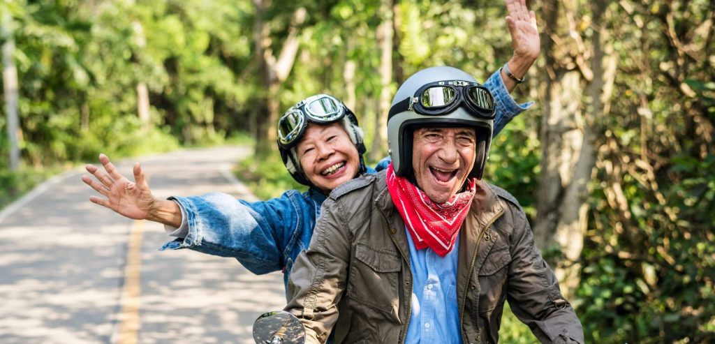 Older couple on a moped driving down the road and smiling