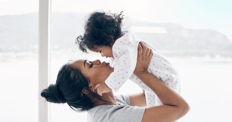 A mother holding her baby daughter at home.
