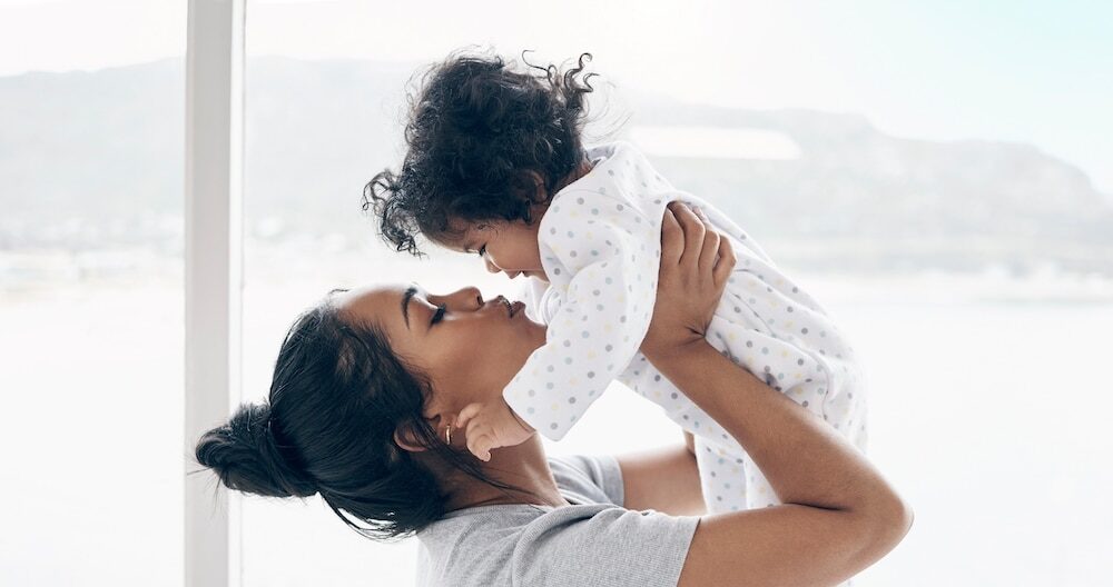 A mother holding her baby daughter at home.