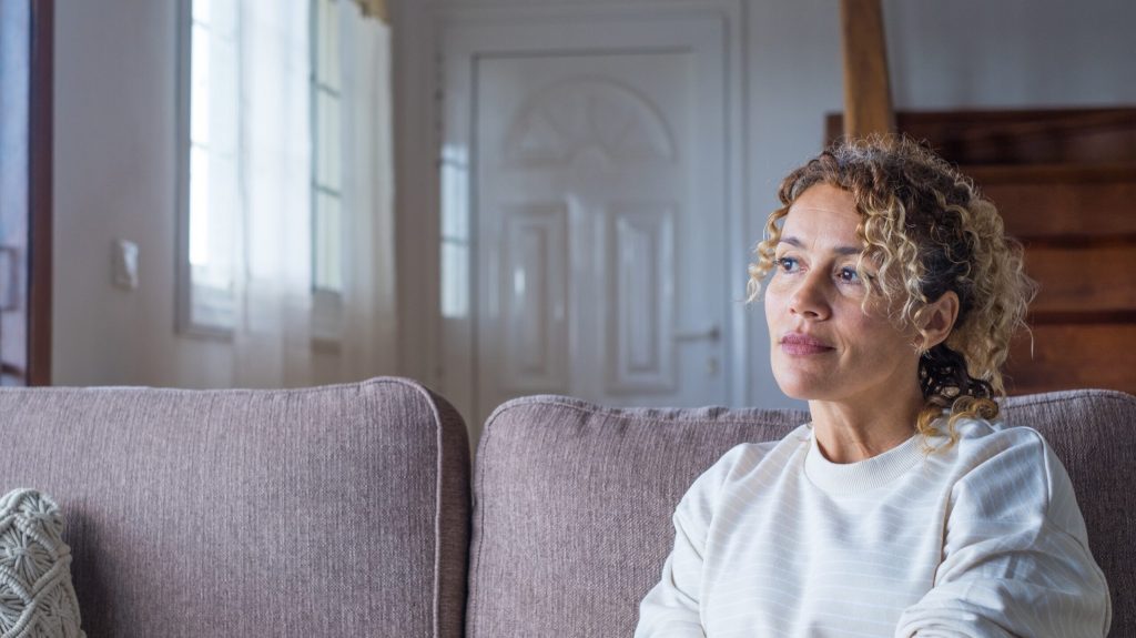 Woman sitting on the couch looking upward while deep in thought