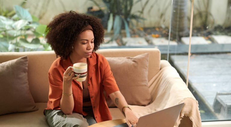 Businesswoman having morning coffee when answering emails