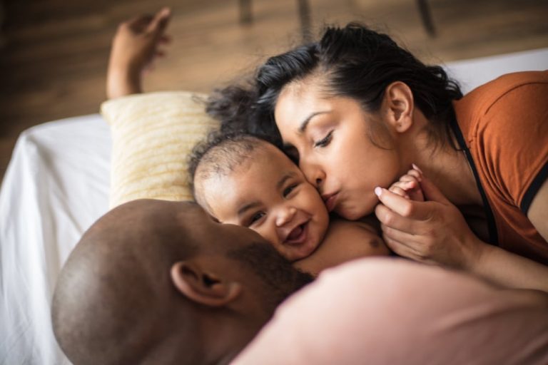 Two new parents kiss their baby on the cheeks after counseling.