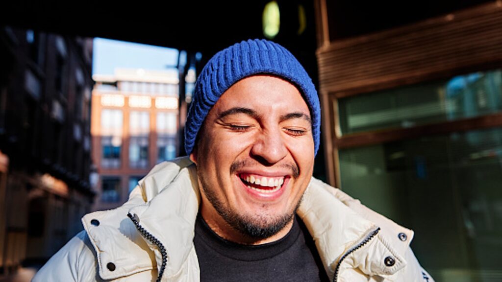 man wearing a blue beanie smiling outside