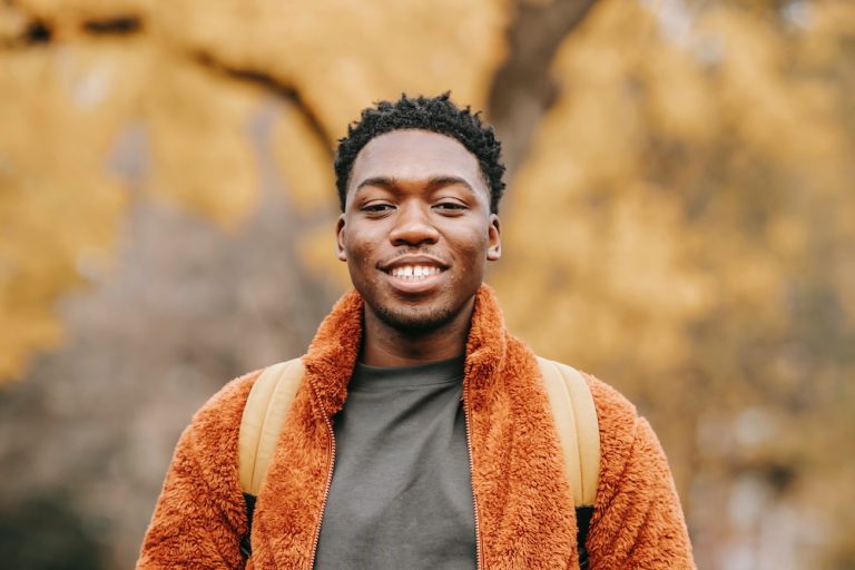 Man standing outside in the fall wearing a bright orange jacket