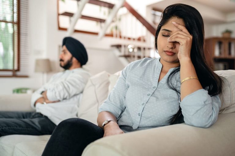 Woman sitting next to a man on the couch with her head in her hands