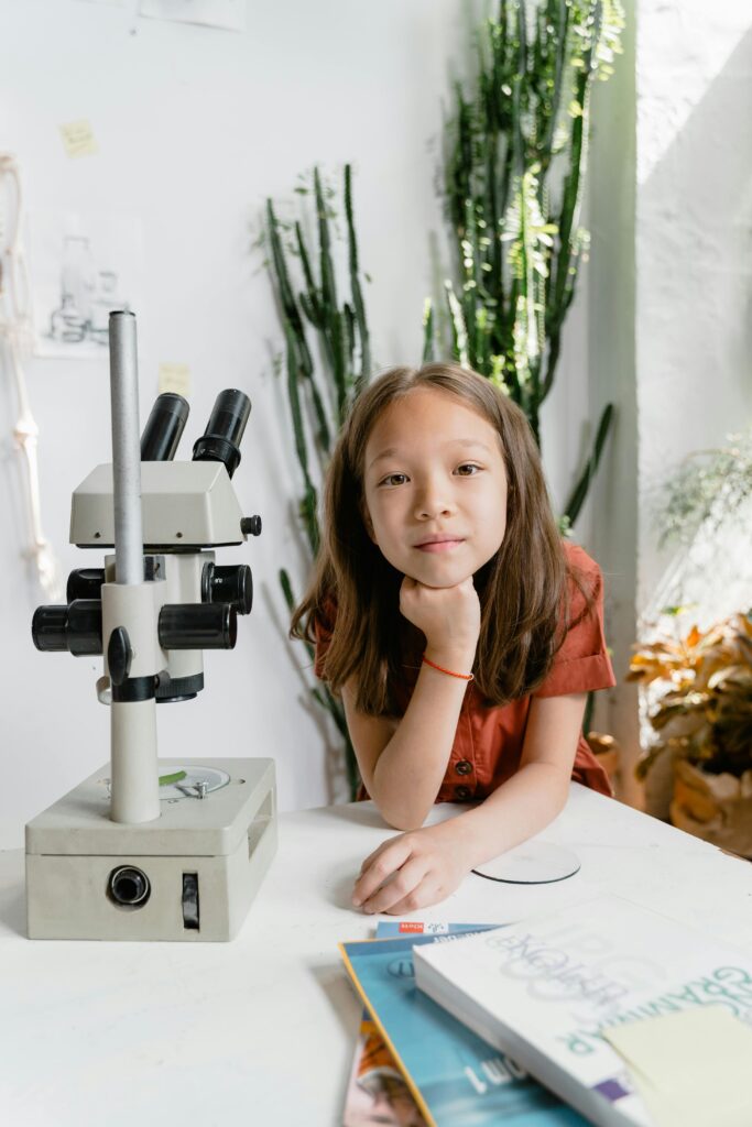 Girl posing for the camera while studying and using a micsoscope