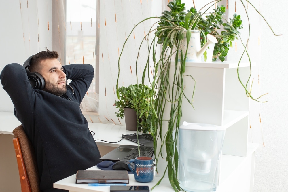 Man in office quiet quitting in the workplace and wearing headphones in relaxed position