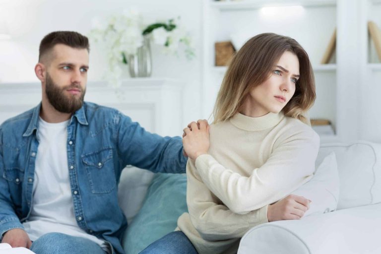 man consoling woman after argument sitting on a sofa
