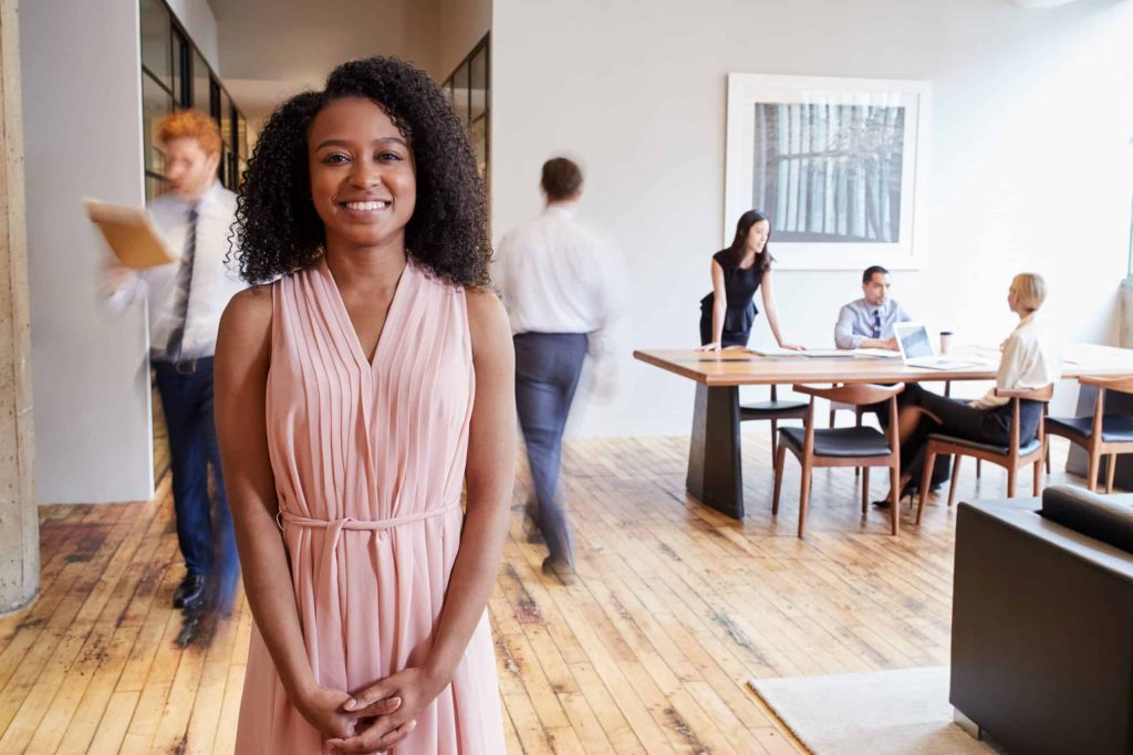 woman standing in an office surrounded by other people