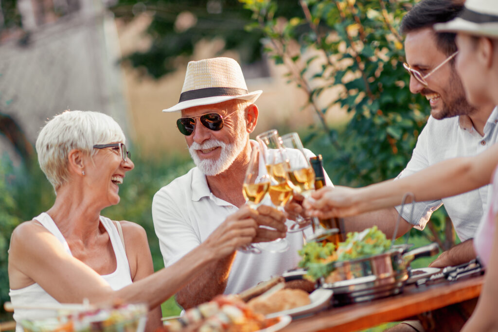 Elderly couple and younger couple outside smiling and having a picnic
