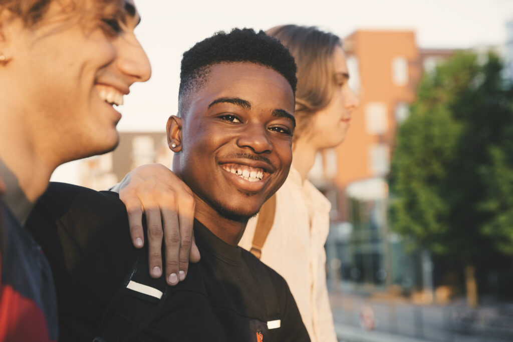 Young adult man sitting with some friends smiling