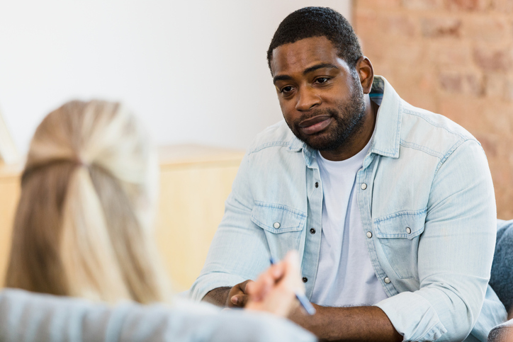 Man sitting on a couch talking to a therapist