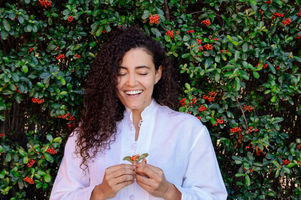 Woman smiling while standing in front of tall bushes