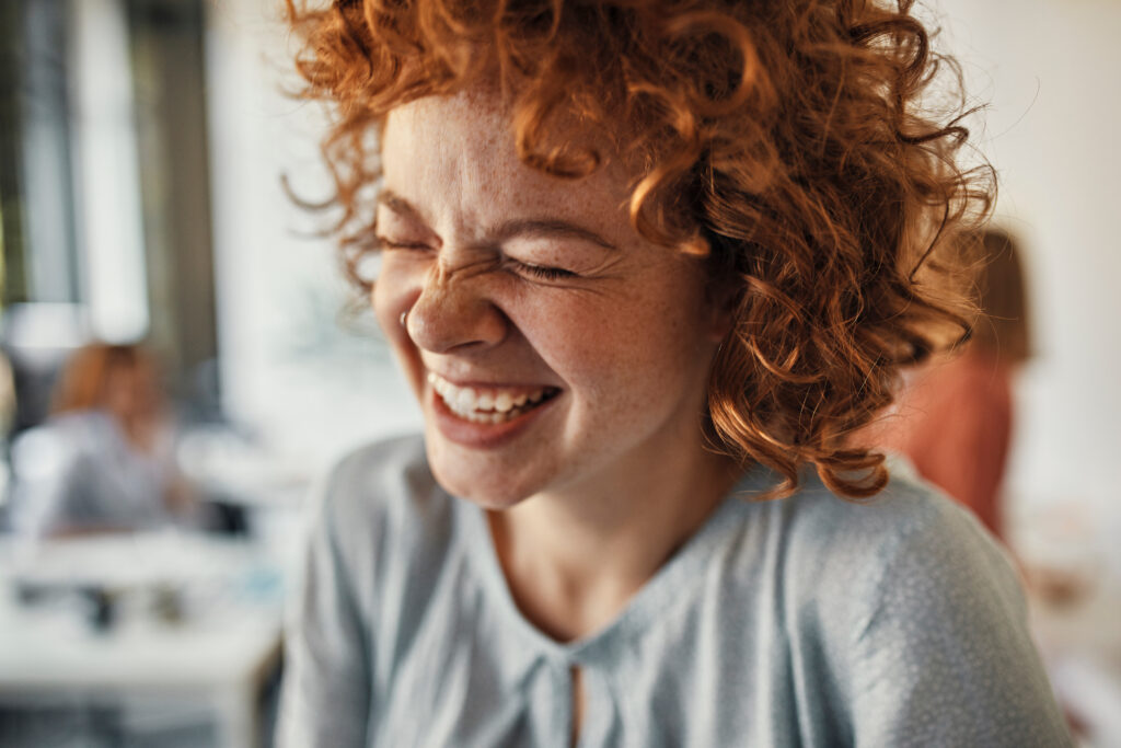 Laughing red haired woman in a grey shirt