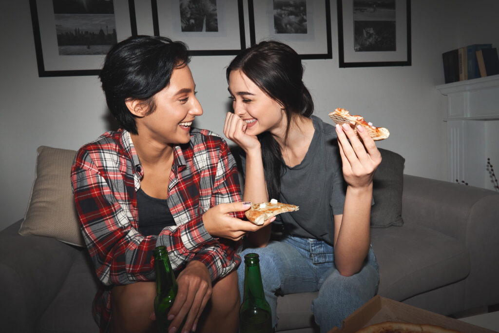 Young adult lesbian couple laughing and eating together