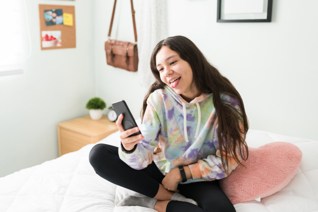 Teenage girl sitting on her bed on a video call