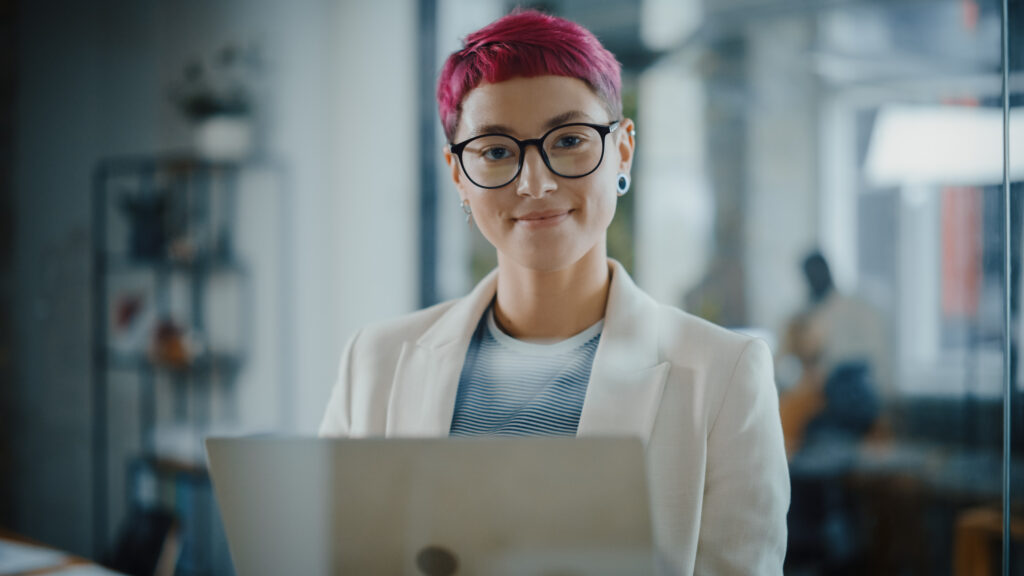 Woman working a corporate job smiling while holding a laptop