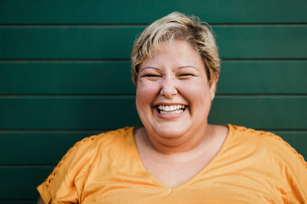 Woman in an orange shirt standing in front of a green wall